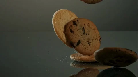 Assorted sweet biscuits falling on reflective surface with crumbs Stock Footage 327580235