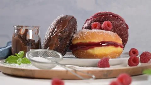 Assorted sweet donuts filled with jam and chocolate served with fresh raspb.. Stock Photos