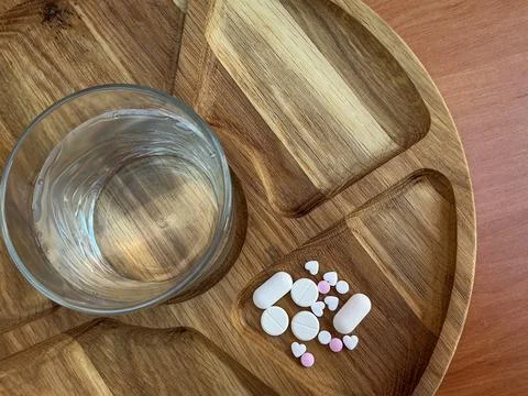 Assorted Tablets and Glass of Water on Rustic Wooden Table Fotos de archivo
