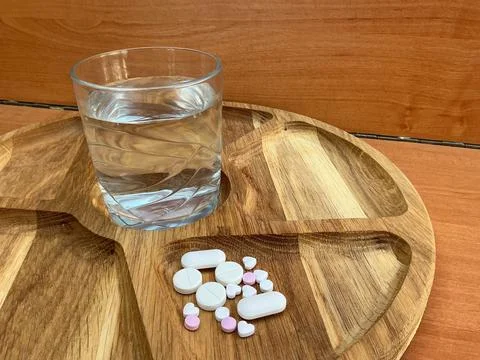 Assorted Tablets and Glass of Water on Rustic Wooden Table Stock Photos