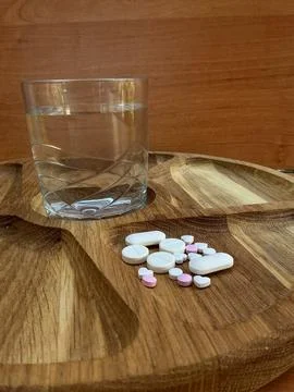 Assorted Tablets and Glass of Water on Rustic Wooden Table Stock Photos