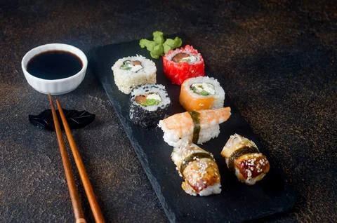 Assorted from tasty sushi rolls set with sauces, ginger and wasabi on dark Stock Photos