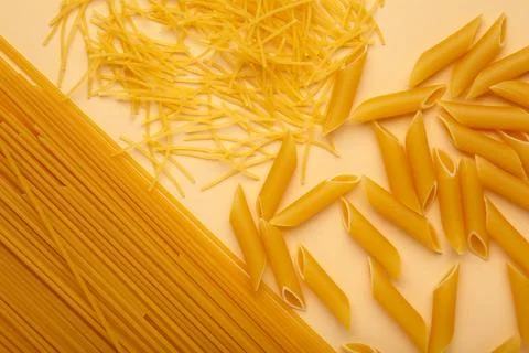 Assorted types of pasta on beige background. Various forms of pasta, spaghett Stock Photos