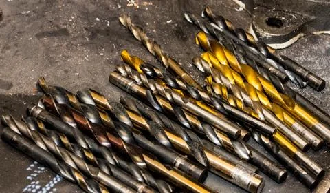 Assorted used drill bits laying on a steel table Stock Photos