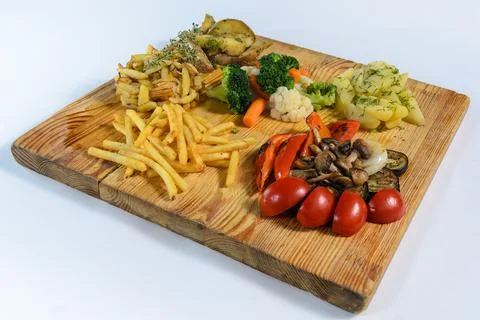 Assorted vegetables and fried potatoes on a cutting board Stock Photos