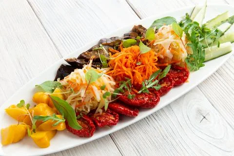 Assorted vegetables in a bowl. Sun-dried tomatoes, pickled squash, cabbage, c Stock Photos