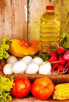 Assorted vegetables , eggs and a bottle of oil on a basket Stock Photos