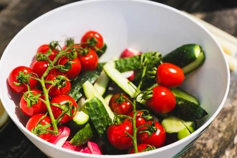 Assorted vegetables. in white bowl. Tomatoes cherry, cucumbers, radish slices Stock Photos