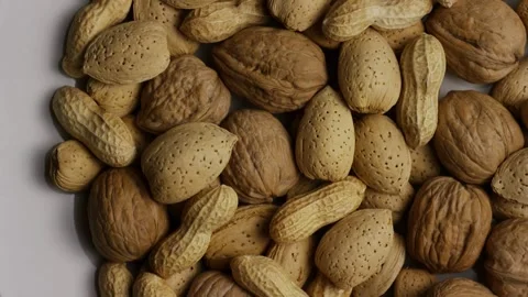 Assorted walnuts almonds and peanuts rotating on white surface Stock Footage 328135786
