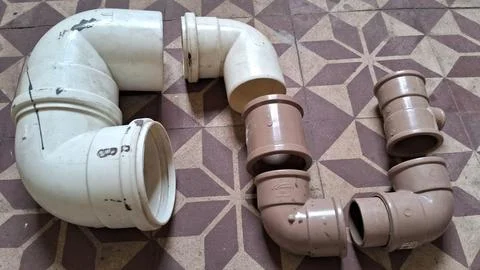 Assorted white and brown plastic plumbing pipes on tiled floor Fotos de archivo