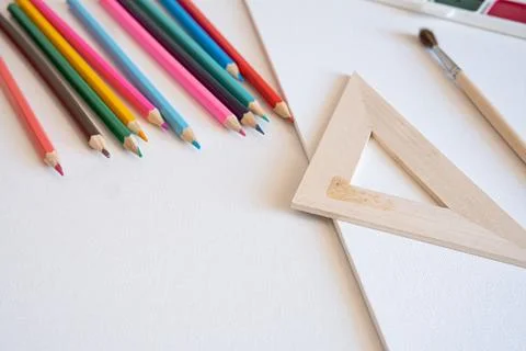 Assorted wooden pencils, drafting triangle, paintbrush, and blank canvas Stock Photos