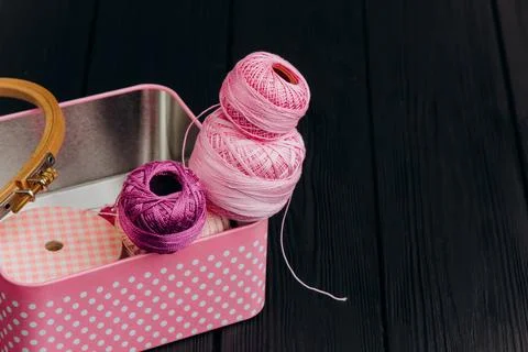 Assorted yarn and sewing tools in a pink tin box on a black wooden backgrou.. Stock Photos