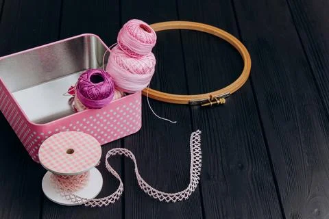 Assorted yarn and sewing tools in a pink tin box on a black wooden backgrou.. Stock Photos