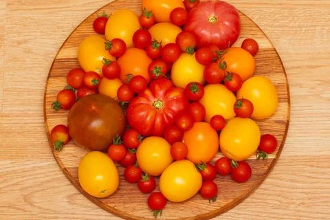 Assorted yellow, pink, cheria, red tomatoes on a wooden background, top view. Stock Photos