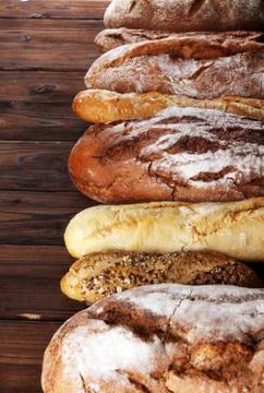 Assortment of baked bread and bread rolls on wooden table background Stock Photos