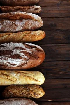 Assortment of baked bread and bread rolls on wooden table background Stock Photos