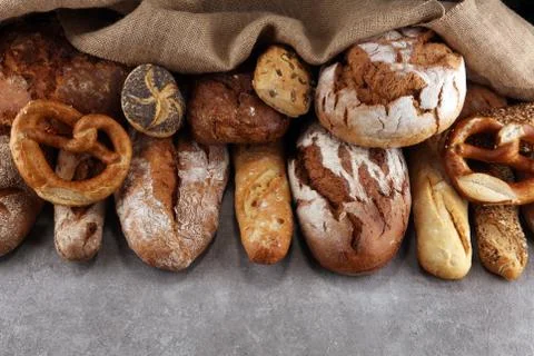 Assortment of baked bread and bread rolls on stone table background Foto stock