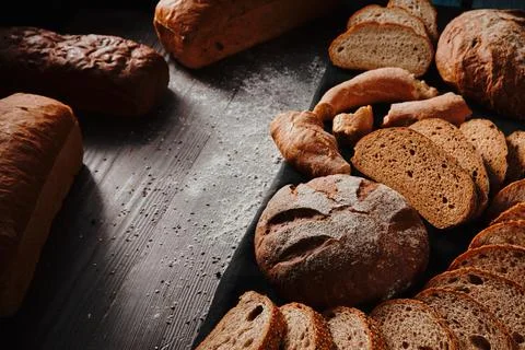 Assortment of baked bread from rye and wheat flour on black background. Top view Stock Photos