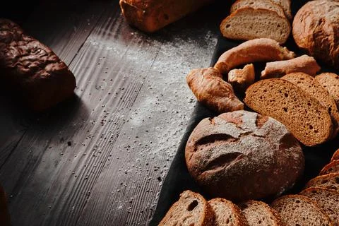 Assortment of baked bread from rye and wheat flour on black background. Top view Stock Photos
