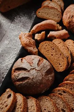 Assortment of baked bread from rye and wheat flour on black background. Top view Stock Photos