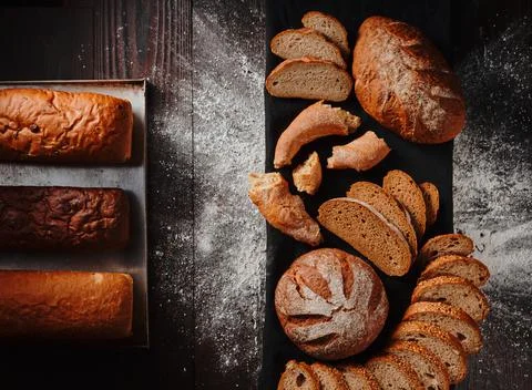 Assortment of baked bread from rye and wheat flour on black background. Top view Stock Photos