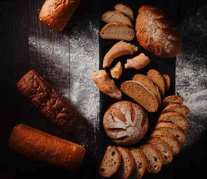 Assortment of baked bread from rye and wheat flour on black background. Top view Stock Photos