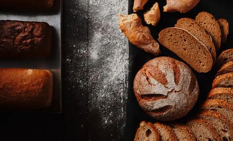 Assortment of baked bread from rye and wheat flour on black background. Top view Stock Photos