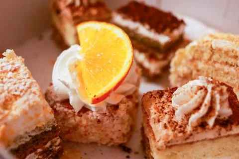 Assortment of bite-sized cream-topped sponge cake squares garnished with thin Stock Photos