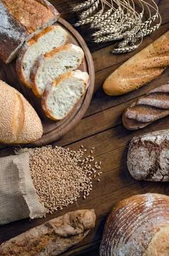Assortment bread products and wheat on wooden table. Stock Photos