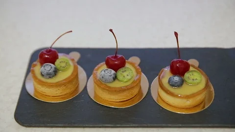 An assortment of cherry and lemon cupcakes topped with honey icings and berries Stock Footage 102368853