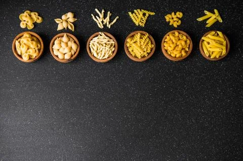Assortment of different dry pasta types against black background, top view. Stock Photos