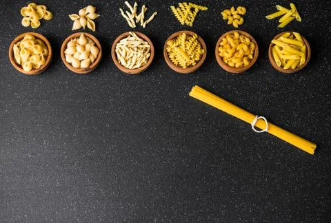 Assortment of different dry pasta types against black background, top view. Stock Photos