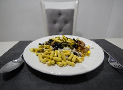 An assortment of different sized pills, vitamins, and supplements on a plate. Stock Photos