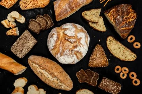 Assortment of different types of bread on a black background. Top view Stock Photos