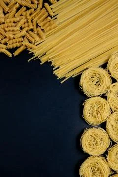 Assortment of different types of pasta dry on black background. Stock Photos