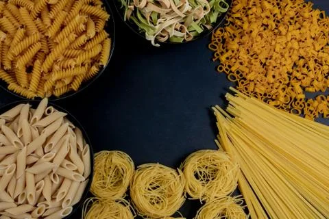 Assortment of different types of pasta dry on black background. Stock Photos