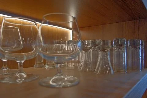 Assortment of Empty Wine Glasses on Rustic Wooden Shelf in Bar. Stock Photos
