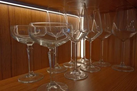 Assortment of Empty Wine Glasses on Rustic Wooden Shelf in Bar. Stock Photos