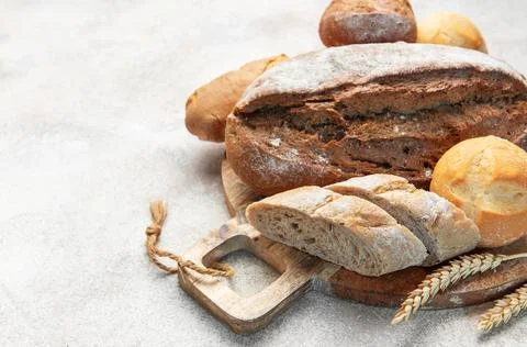 Assortment of fresh baked bread on rustic wooden board Stock Photos