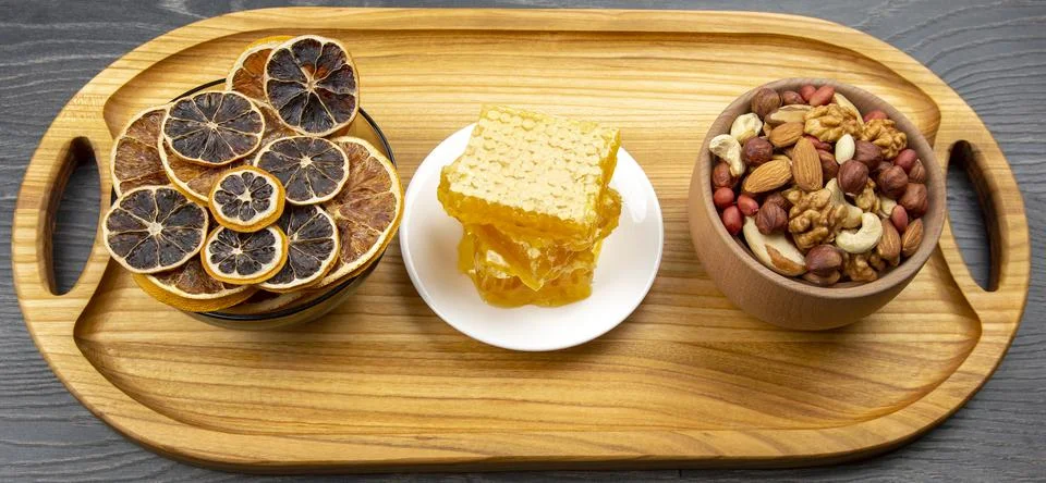 Assortment of nuts and assorted dried citrus fruits and fresh floral honeycom Stock Photos