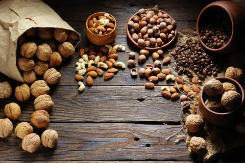 Assortment of nuts and coffee beans scattered on rustic wooden table Stock-Fotos