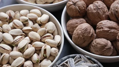 Assortment of nuts in different bowls: walnut, peanut, pistachio and sunflowe Stock Footage 159953014