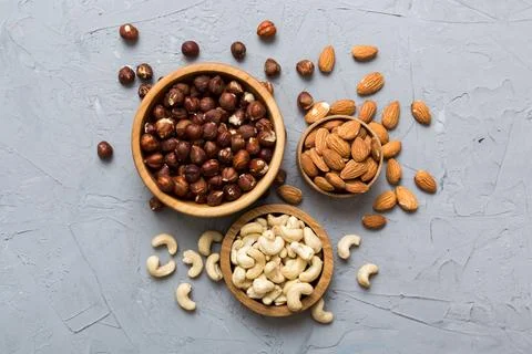 Assortment of nuts in wooden bowl on colored table. Cashew, hazelnuts, walnut Stock Photos