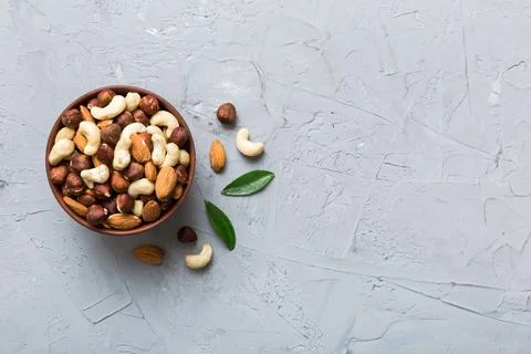Assortment of nuts in wooden bowl on colored table. Cashew, hazelnuts, walnut Stock Photos