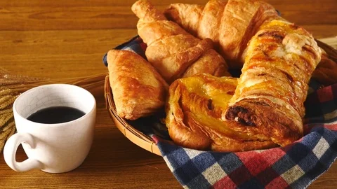 Assortment of pastries with coffee on wooden table background. Stock Footage