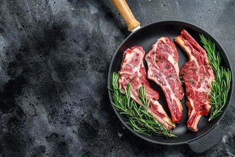 Assortment of raw cuts beef meat steaks in a pan. Black background. Top view Stock Photos