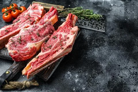 Assortment of raw cuts beef meat steaks on the bone. Black background. Top view Stock Photos
