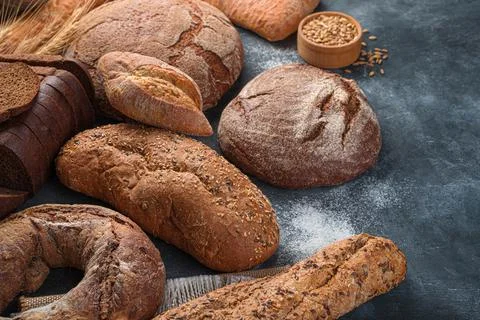 Assortment of rye and wheat bread on a dark background with flour. Stock Photos