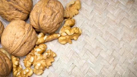 Assortment of walnut shells and walnut kernels on light wicker surface, with Stock Photos