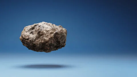 Asteroid Spinning on Studio Blue Background Stock Footage 239738597